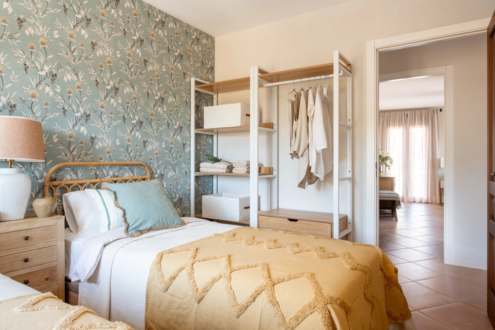 Dormitorio de invitados en Casa El Pantano, proyecto de interiorismo en Zufre, Huelva, con papel pintado botánico, mobiliario ligero y decoración cálida de inspiración natural.