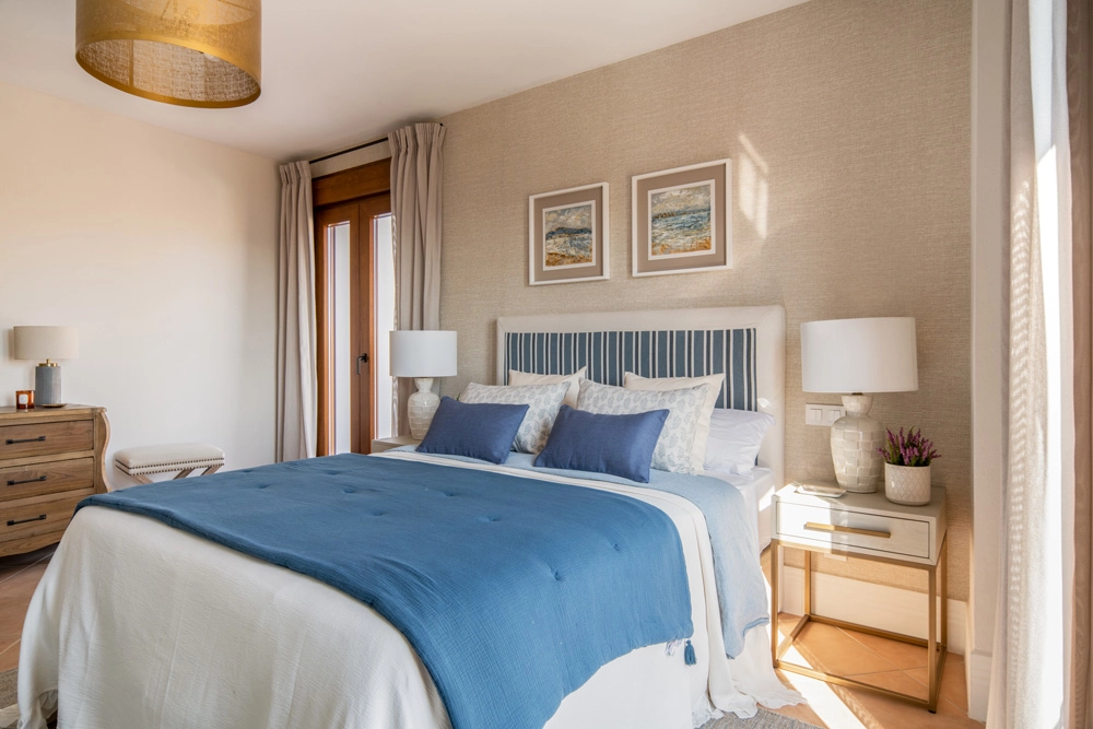 Dormitorio en casa rural en Zufre, Huelva, diseñado por Elizabeth Herrero Estudio con interiorismo cálido, textiles en tonos azules y estética rústico contemporánea.